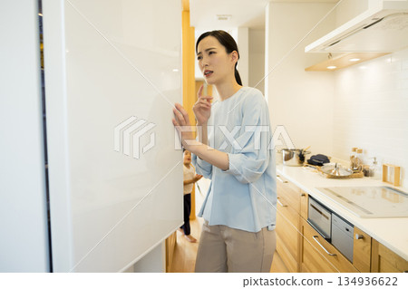 A woman who opens a refrigerator 134936622