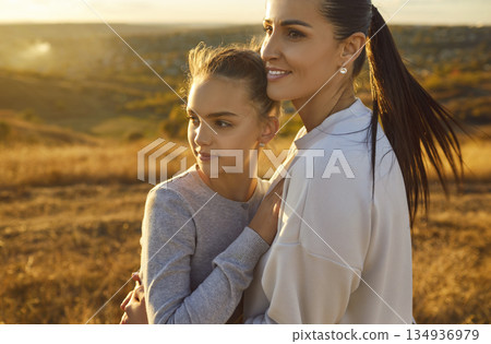 Young smiling mother standing in the field with her happy child daughter outdoor. Young smiling mother standing in the field with her happy child daughter outdoor. 134936979