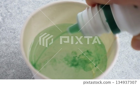 Person adding mouthwash to water Person adding mouthwash to water 134937307