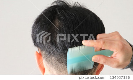 Back view of a Japanese man combing his hair Back view of a Japanese man combing his hair 134937326