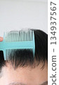 A Japanese man with thinning hair combing his hair 134937567