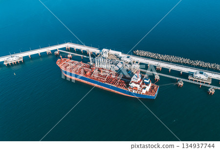 Aerial view of a large oil tanker docked at a pier in the port in process of loading. 134937744
