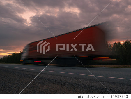Large truck moving quickly along a highway during a vibrant sunset with dramatic clouds in the background Large truck moving quickly along a highway during a vibrant sunset with dramatic clouds in the background 134937750