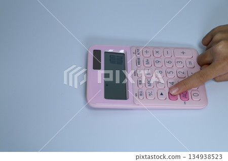 一隻女人的手正在操作計算機和一台粉紅色的計算機。 一隻女人的手正在操作計算機和一台粉紅色的計算機。 134938523