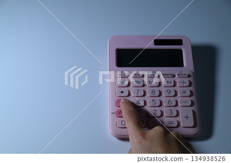 一位女士的指尖正在操作一台粉紅色計算器。 134938526