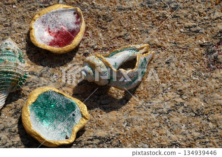 Seashells on a stone background. Several colorful, shiny seashells lie on a multi-colored stone.Seashells on a stone background. Seashells on a stone background. Several colorful, shiny seashells lie on a multi-colored stone.Seashells on a stone background. 134939446