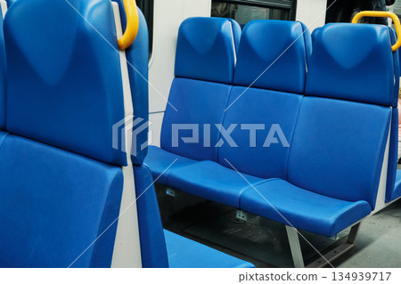 Blue vinyl seats in row, with yellow grab handle, inside an empty public transportation coach Blue vinyl seats in row, with yellow grab handle, inside an empty public transportation coach 134939717