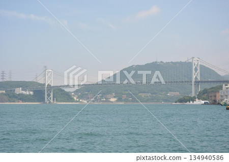 Panoramic view of the Kanmon Strait from Mojiko Port: The huge Kanmon Bridge and large ships passing by 134940586