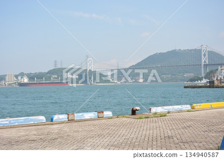 Panoramic view of the Kanmon Strait from Mojiko Port: The huge Kanmon Bridge and large ships passing by 134940587