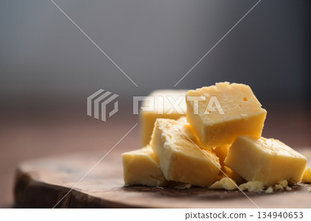 White cheddar cheese pieces on olive wood board 134940653