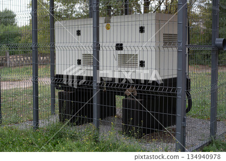 Installation of a large industrial fuel-fired generator on a green lawn. A mobile power source, backup equipment for power plants.  134940978
