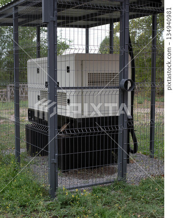 Installation of a large industrial fuel-fired generator on a green lawn. A mobile power source, backup equipment for power plants.  134940981