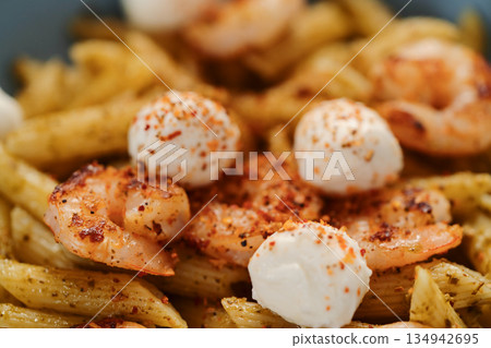 Penne pasta with shrimps and mozzarella and pesto in blue bowl 134942695