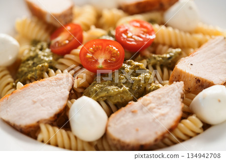 fussili pasta with chicken fillet, tomatoes, mozzarella and pesto sauce in white bowl closeup fussili pasta with chicken fillet, tomatoes, mozzarella and pesto sauce in white bowl closeup 134942708