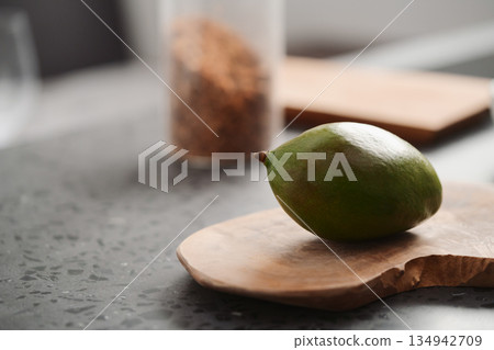 Whole geen mango on olive board on kitchen countertop Whole geen mango on olive board on kitchen countertop 134942709
