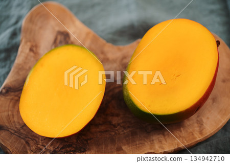 Sliced ripe red mango on olive wood board Sliced ripe red mango on olive wood board 134942710