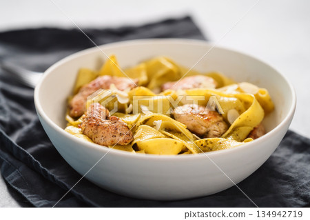 Pasta tagliatelle with chicken, pest and almonds in white bowl Pasta tagliatelle with chicken, pest and almonds in white bowl 134942719