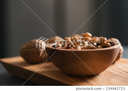 Walnuts in wooden bowl on olive board Walnuts in wooden bowl on olive board 134942723