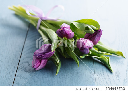 bunch of purple tulips on blue wood table 134942730