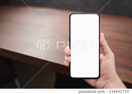 Man hand hold phone with white screen over black walnut table background Man hand hold phone with white screen over black walnut table background 134942734