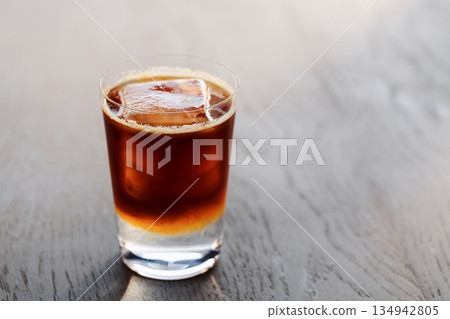 Espresso tonic with clear ice cube in tumbler glass on oak wood table with copy space Espresso tonic with clear ice cube in tumbler glass on oak wood table with copy space 134942805