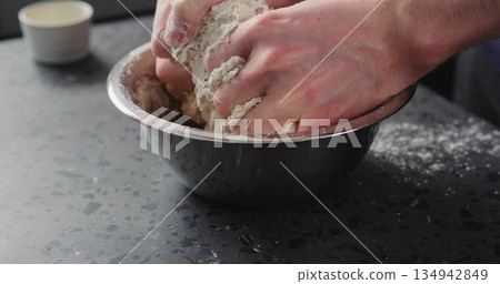 man mixing dough in steel bowl on concrete countertop man mixing dough in steel bowl on concrete countertop 134942849
