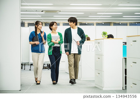 Young men and women walking while talking with colleagues 134943556