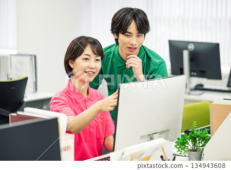 穿著polo衫的年輕男女在辦公室做案頭工作。 穿著polo衫的年輕男女在辦公室做案頭工作。 134943608