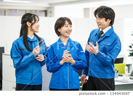 身穿藍色工作服的年輕男女在辦公室交談 身穿藍色工作服的年輕男女在辦公室交談 134943697