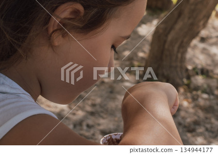Child eating ice cream from a paper cup with an eco-friendly wooden spoon outdoors Child eating ice cream from a paper cup with an eco-friendly wooden spoon outdoors 134944177