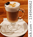 Latte coffee with milk foam art and pine cone garnish in glass. 134944662