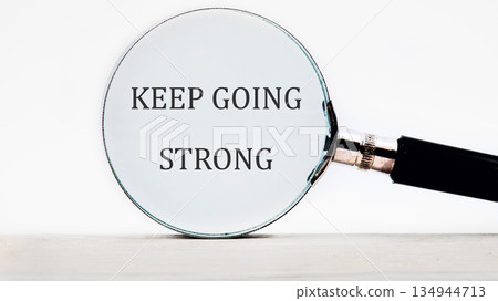A magnifying glass is placed over the words KEEP GOING STRONG, amplifying the message of perseverance. The crisp focus draws attention to the power of resilience A magnifying glass is placed over the words KEEP GOING STRONG, amplifying the message of perseverance. The crisp focus draws attention to the power of resilience 134944713