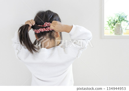 一個女孩(5歲,日本人,黑髮)正在嘗試把頭髮綁成馬尾。 一個女孩(5歲,日本人,黑髮)正在嘗試把頭髮綁成馬尾。 134944953