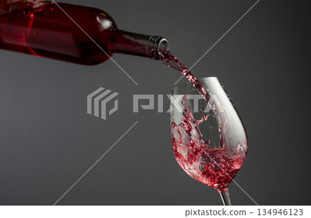 Pouring pink wine from a bottle into a glass. 134946123