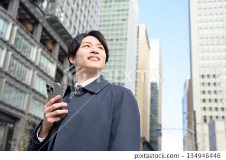 Japanese man using a smartphone in an office district Japanese man using a smartphone in an office district 134946446