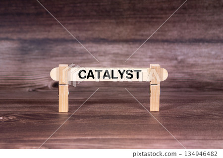 Catalyst symbol. Clothespins gripping a wooden stick against a beautiful Brown Wooden Background . Business and Catalyst concept with copy space Catalyst symbol. Clothespins gripping a wooden stick against a beautiful Brown Wooden Background . Business and Catalyst concept with copy space 134946482
