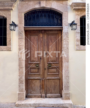Ornate wooden door with stone archway and retro lamps Ornate wooden door with stone archway and retro lamps 134946604