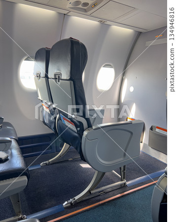 Empty airplane cabin seats next to bright windows 134946816