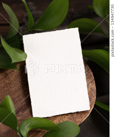 Vertical card on brown wooden tray near green leaves and grey linen cloth closeup, boho mockup Vertical card on brown wooden tray near green leaves and grey linen cloth closeup, boho mockup 134947730