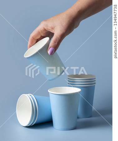 Female hand with disposable light blue paper cup closeup, mockup, copy space. Single-use cup 134947738