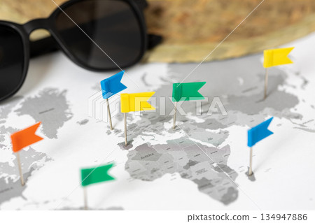 World map marking travel destinations with colorful flag pins, sunglasses and straw hat. Vacation, travel concept World map marking travel destinations with colorful flag pins, sunglasses and straw hat. Vacation, travel concept 134947886