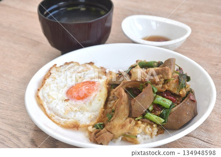 spicy fried slice pork organ with basil topping egg on rice in plate dipping chili fish sauce eat couple clear soup spicy fried slice pork organ with basil topping egg on rice in plate dipping chili fish sauce eat couple clear soup 134948598