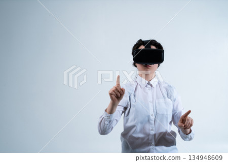 Woman wearing virtual reality headset and selecting digital elements with finger using futuristic human computer interaction technology 134948609
