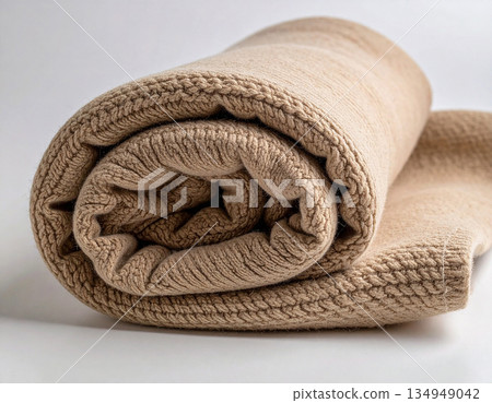 Delicate texture. Beige tones. Rolled up comforter. Wool throw blanket on a white background. Minimalist luxury living room. Delicate texture. Beige tones. Rolled up comforter. Wool throw blanket on a white background. Minimalist luxury living room. 134949042