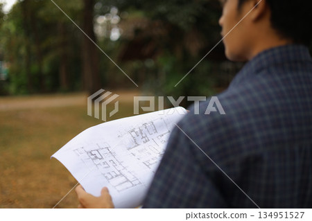 Construction Professional Holding Blueprints at Building Site 134951527