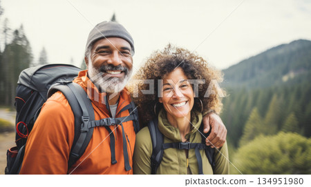 Middle aged couple walking on forest path with backpacks in summer 134951980