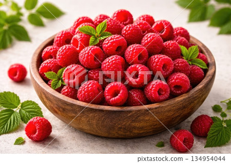 Fresh Raspberries in Wooden Bowl with Green Leaves on Light Background Fresh Raspberries in Wooden Bowl with Green Leaves on Light Background 134954044