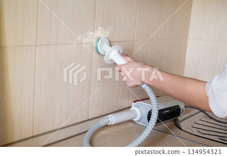 Using a kitchen appliance for cleaning on a cabinet surface in a modern home setup 134954321