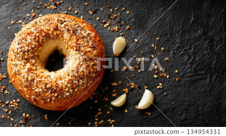 Everything Bagel with Garlic Cloves on Dark Slate Background Everything Bagel with Garlic Cloves on Dark Slate Background 134954331