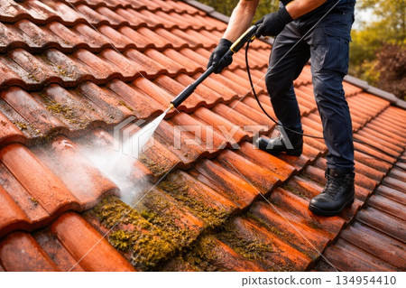 Professional Roof Cleaning Service Using High Pressure Washer on Tile Roof Professional Roof Cleaning Service Using High Pressure Washer on Tile Roof 134954410